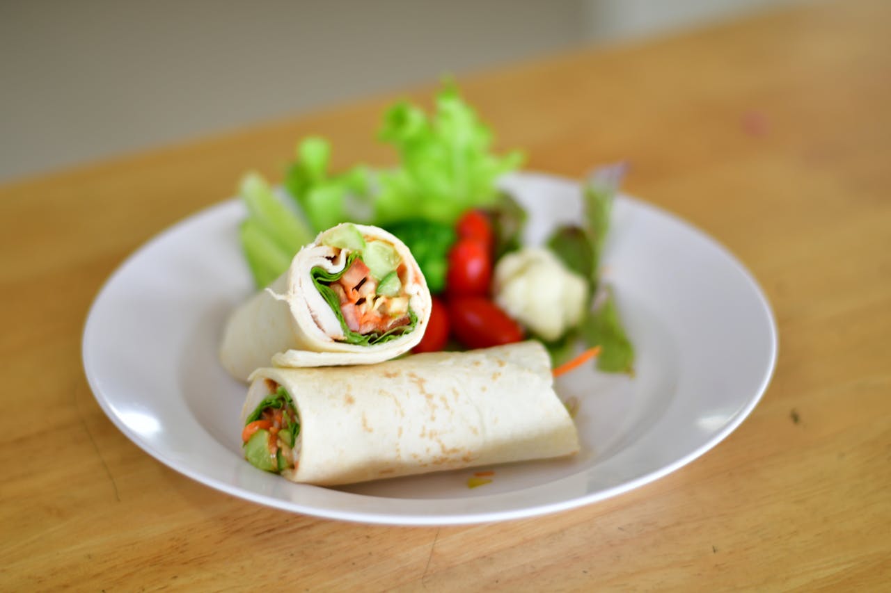 Delicious vegetable wraps served on a white plate with fresh salad.